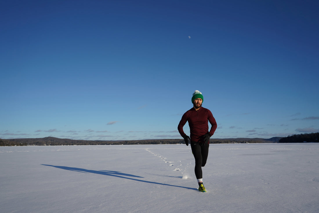 A man stands on a snowy landscape after a run, embodying active skincare with his winter gear, ready for a post-workout skin routine.